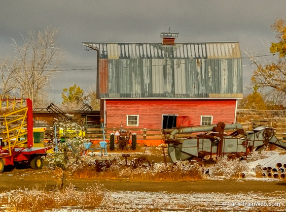 Snow clouds and Red Barn with antique farm machinery north of Trinidad, Colorado.